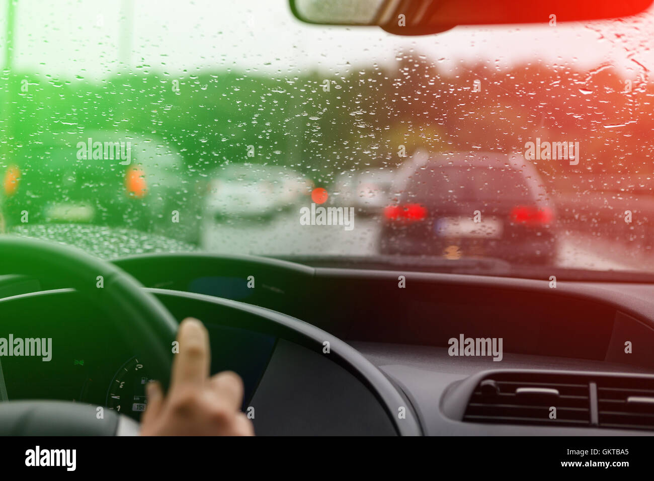 Cattive condizioni meteorologiche alla guida di una vettura in ingorghi di traffico in verde e le luci rosse Foto Stock