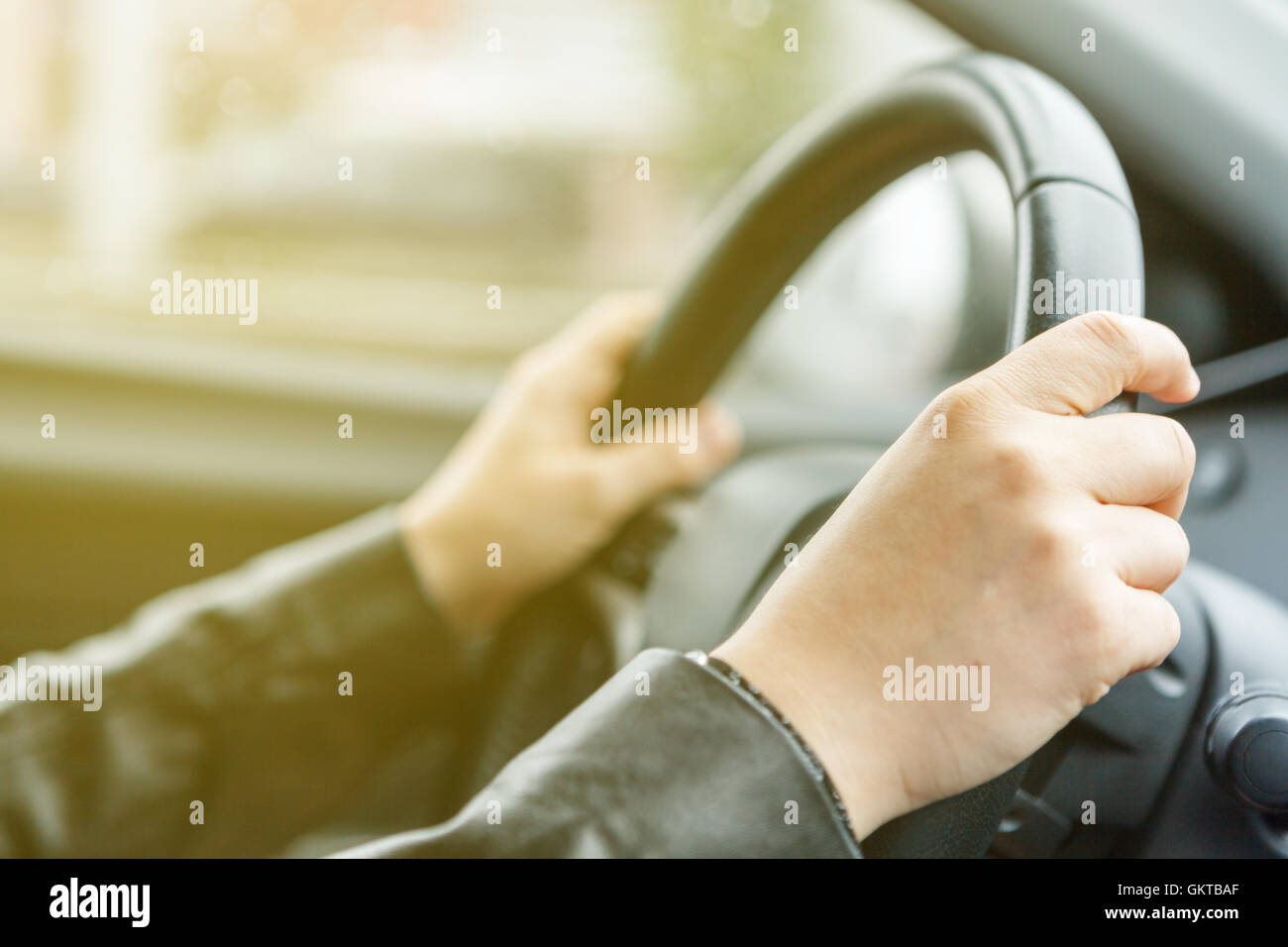 Donna alla guida di una vettura e le mani sul volante di sterzo, stile di sunrise Foto Stock