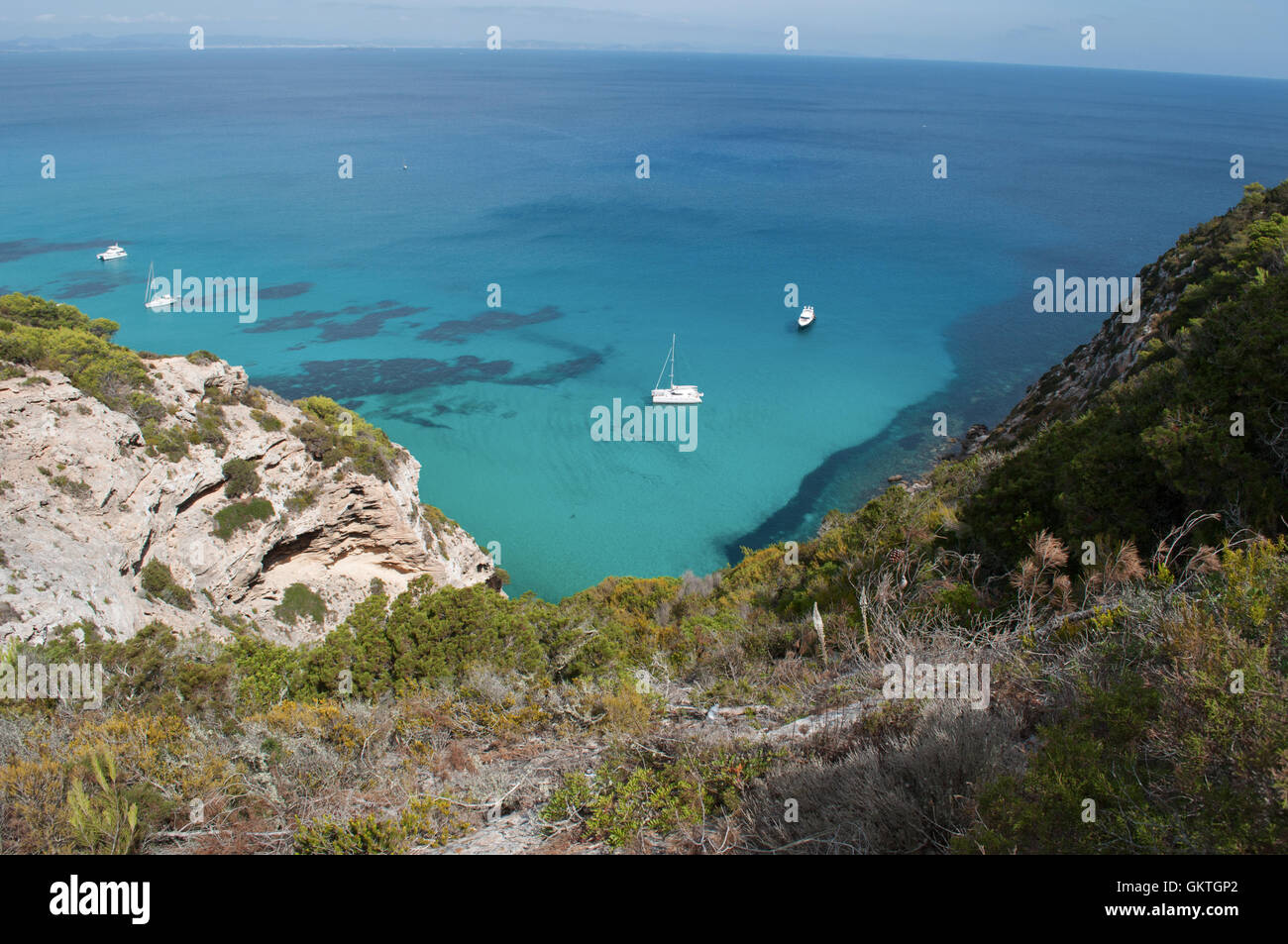 Formentera Isola delle Baleari: vista della macchia mediterranea, un catamarano e barche nel Mare Mediterraneo Foto Stock