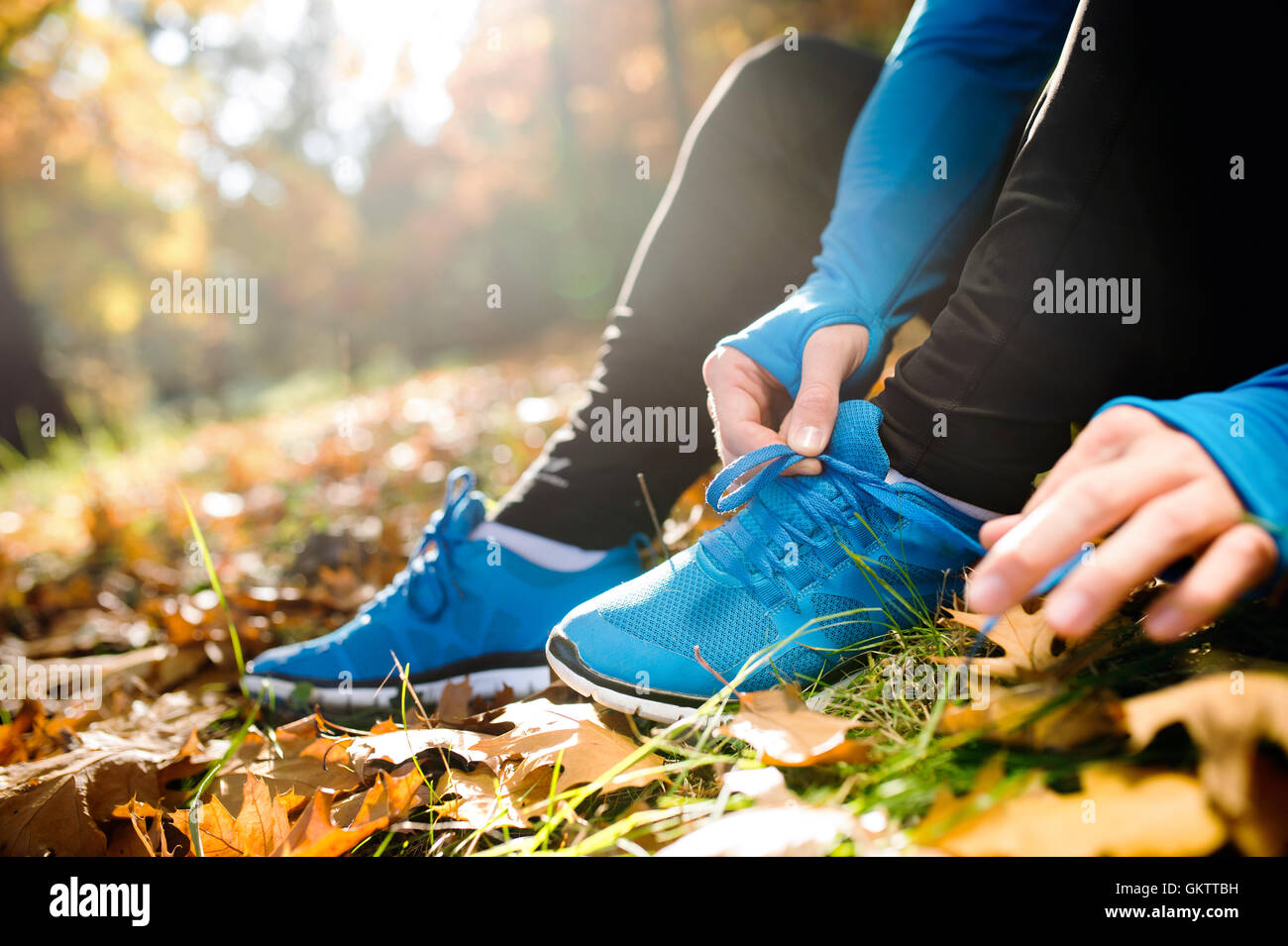 Irriconoscibile runner seduto a terra, la legatura lacci delle scarpe, au Foto Stock