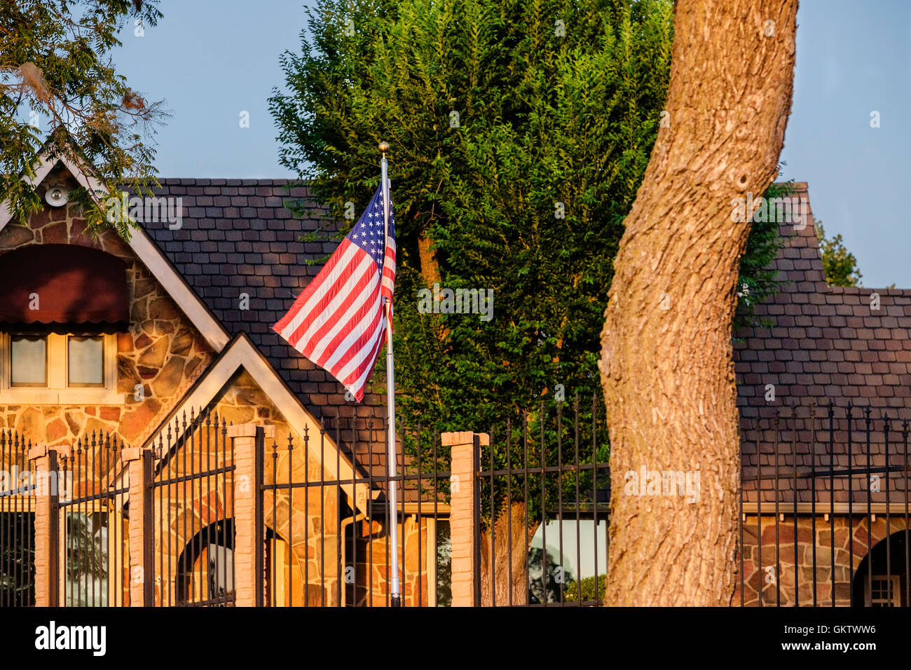 Una casa nella città di Oklahoma, Oklahoma, Stati Uniti d'America, sventola la bandiera americana su un pennone. Luce della Sera. Foto Stock