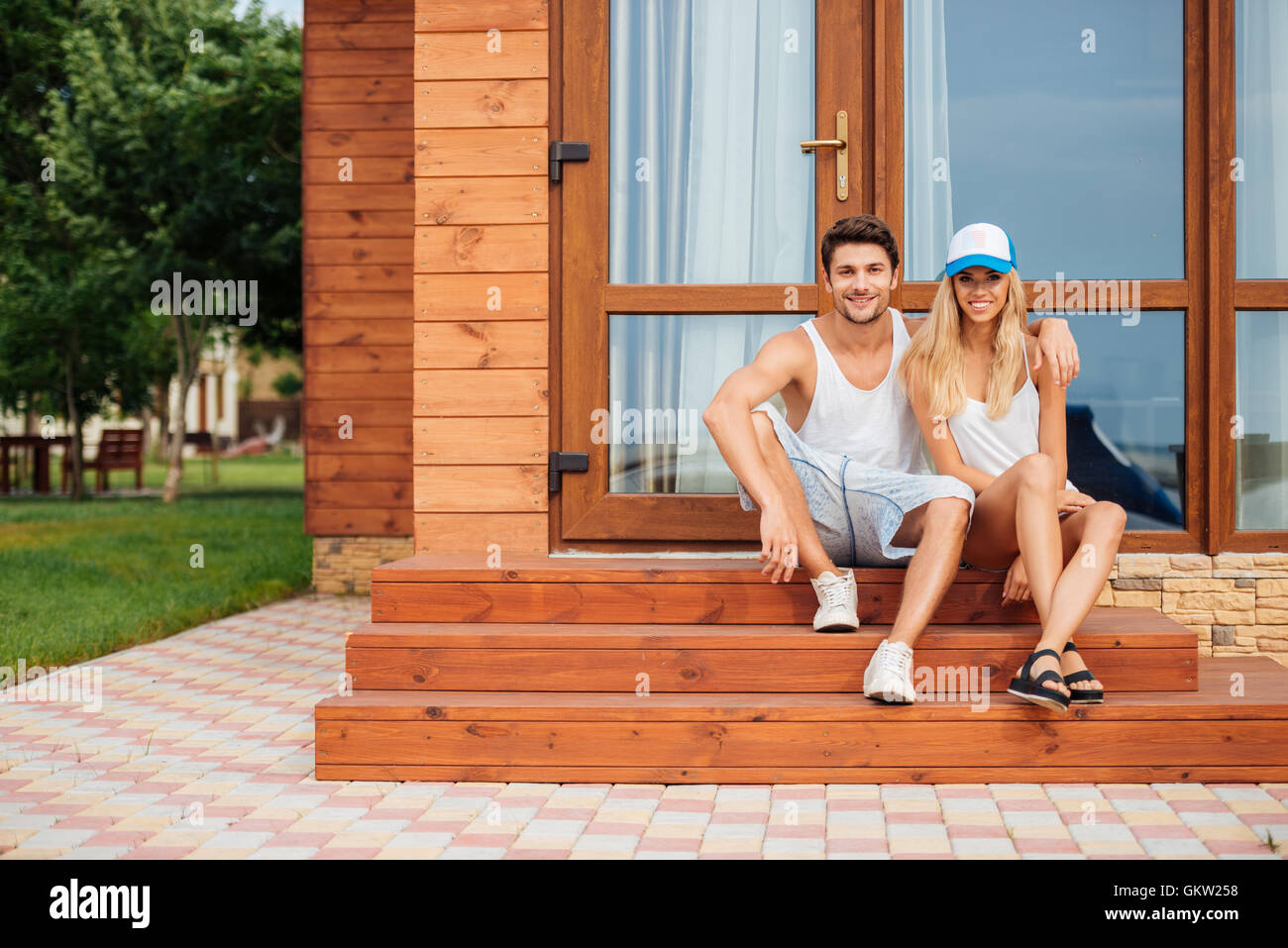 Felice coppia giovane seduto e abbracciando il portico di casa Foto Stock