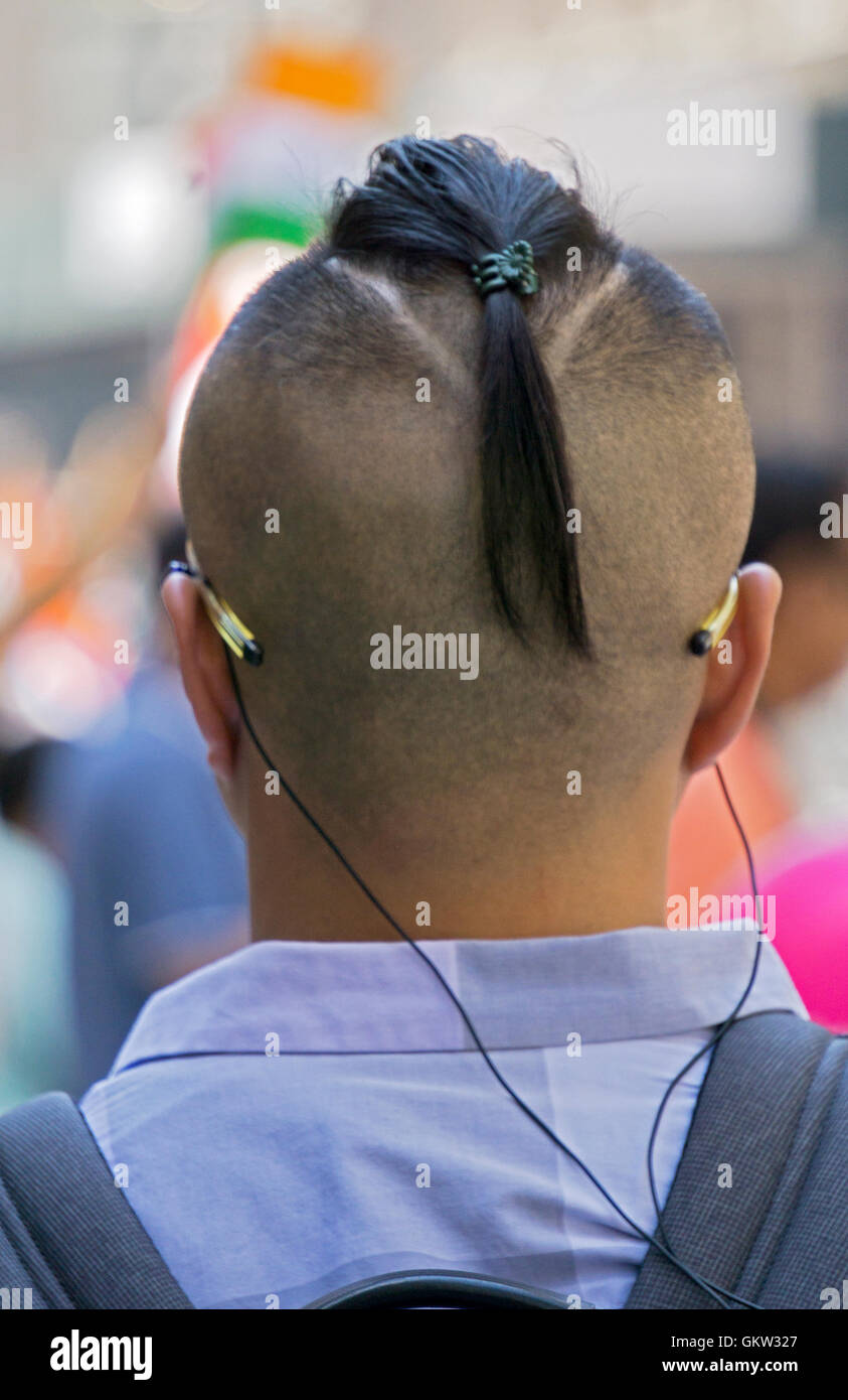 Vista dal retro di un americano asiatico con un insolito taglio di capelli. Om Madison Avenue nel centro di Manhattan, New York City. Foto Stock