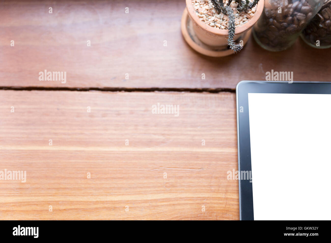 Tablet, cactus pot e chicco di caffè in bottiglia sulla scrivania in legno - vista superiore Foto Stock