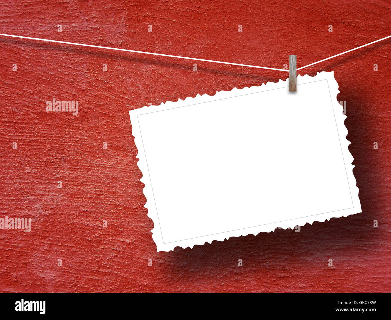 Close-up di uno sbozzato telaio cartolina impiccato da peg contro rosso muro intonacato sfondo Foto Stock