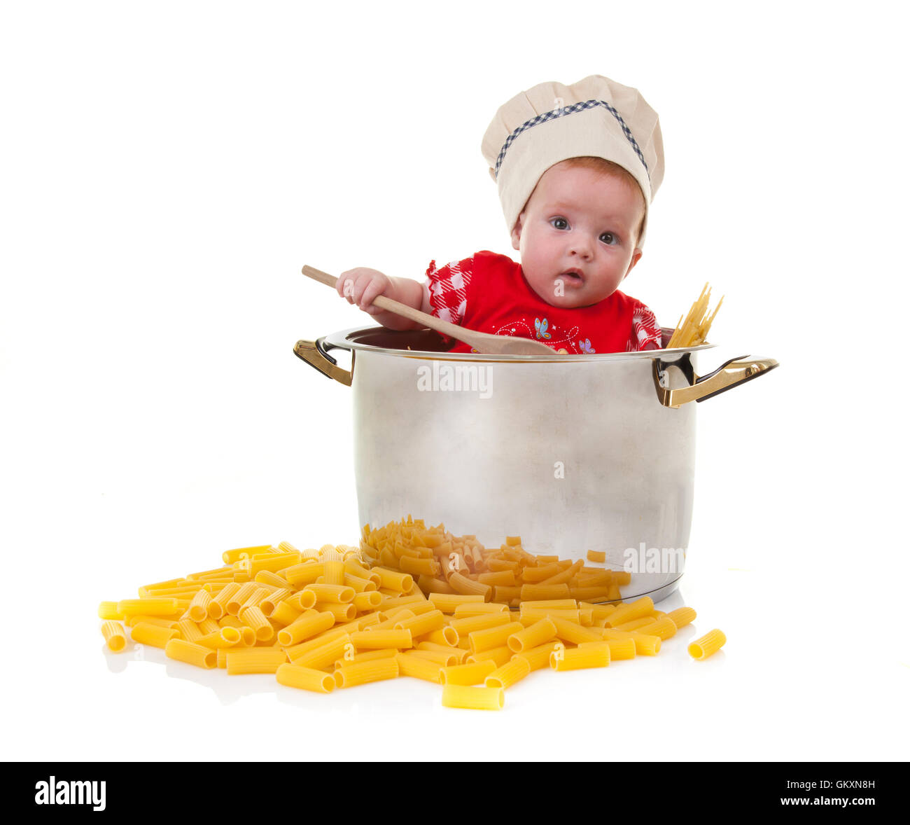 Carino baby chef in una grande pentola con la pasta su sfondo bianco. Foto Stock