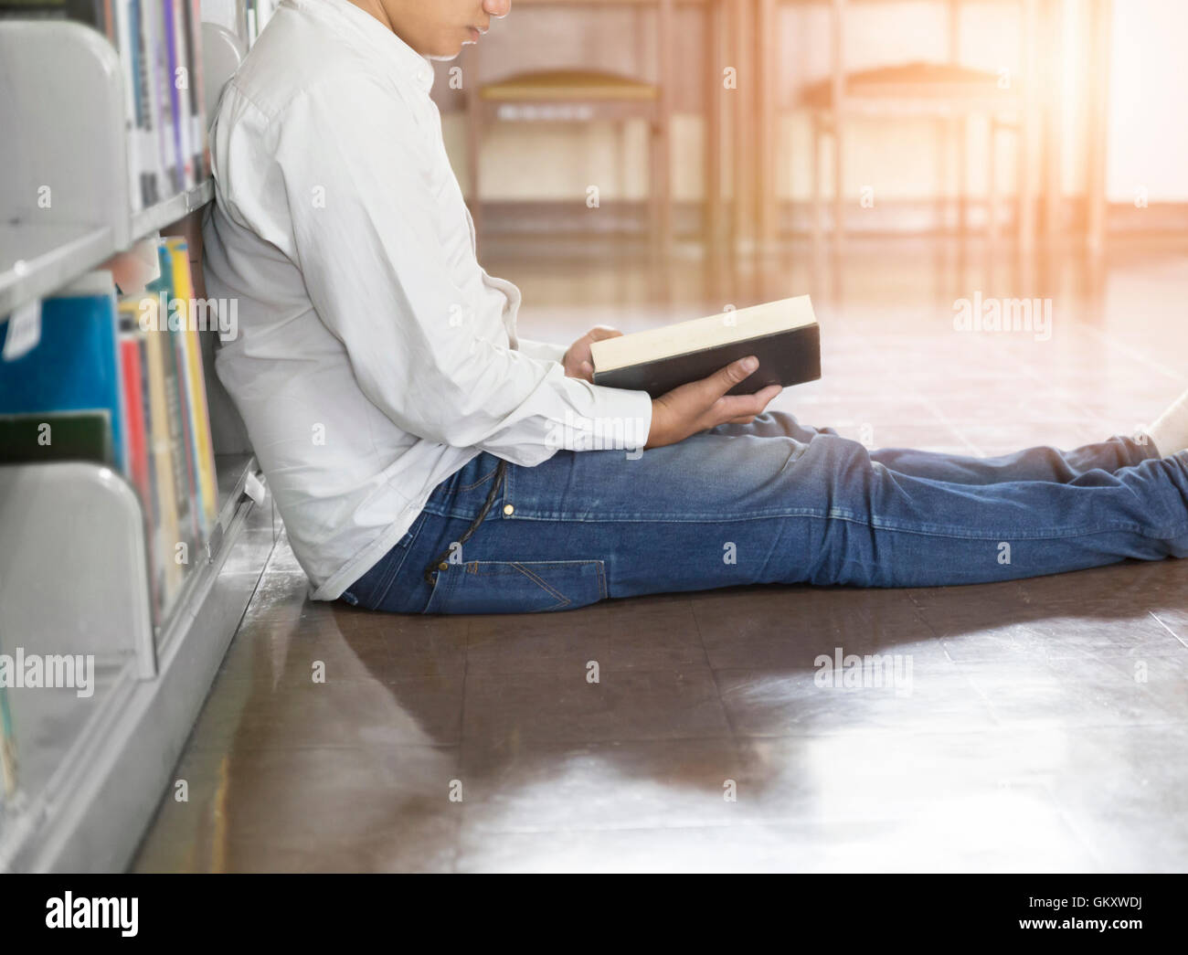 Uomo seduto e la lettura di un libro sul piano nella corsia in biblioteca Foto Stock