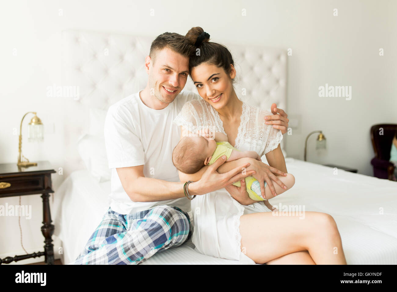 La famiglia felice con il neonato sul letto in camera Foto Stock