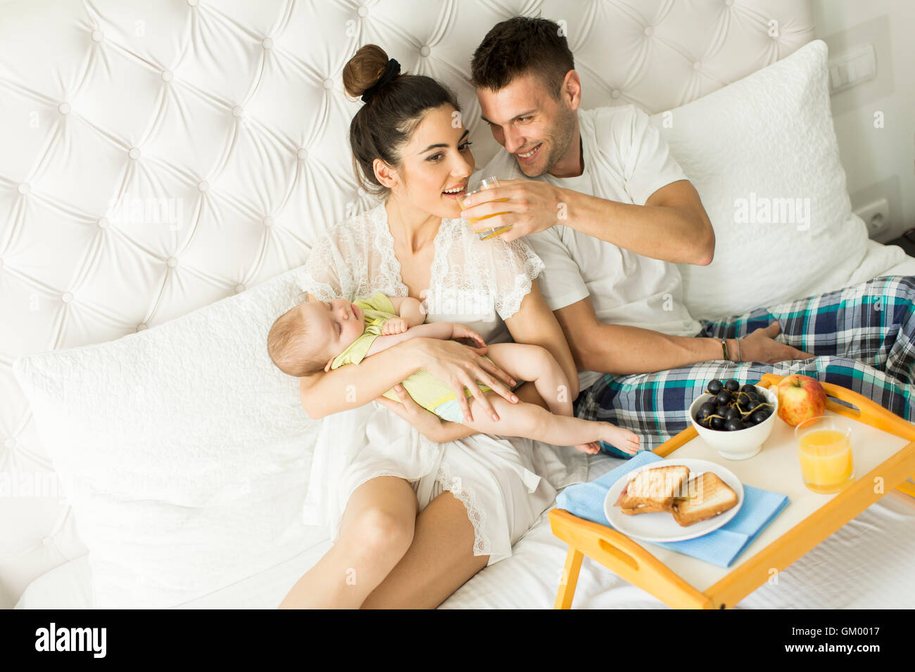 I giovani genitori con baby girl avente la colazione a letto Foto Stock