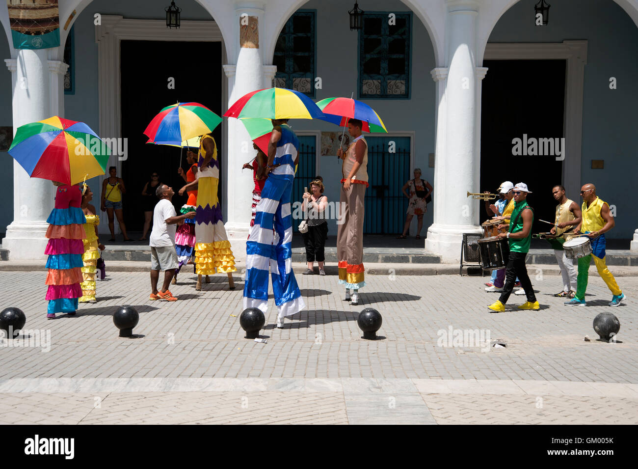 Un gruppo di musicisti di carnevale su palafitte vestiti con costumi intrattiene i turisti in Plaza de Vieja a la Habana Cuba Foto Stock