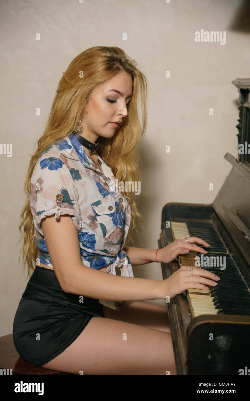 Bella ragazza bionda con capelli sciolti sta giocando sul pianoforte Foto Stock