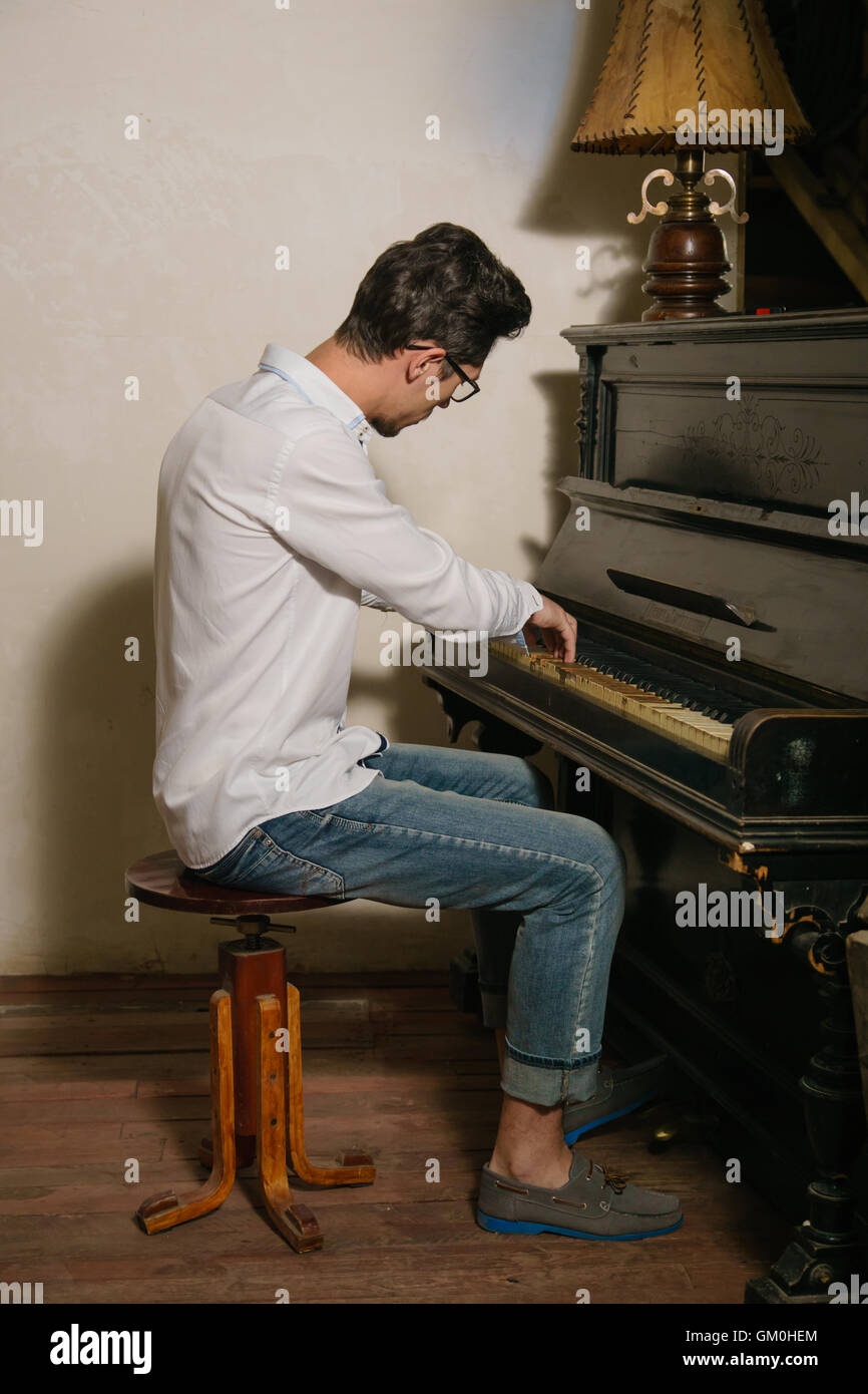 Dai capelli scuri è uomo giocando sul pianoforte seduti sulla sedia. Egli è ispirato da questo gioco Foto Stock