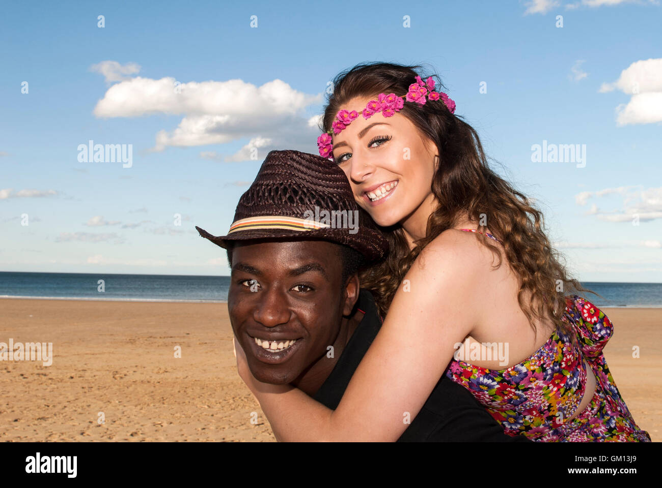 Multiculturale di razza mista coppia giovane a beach piggybacking ridendo felice avendo divertimento testa e spalle Foto Stock