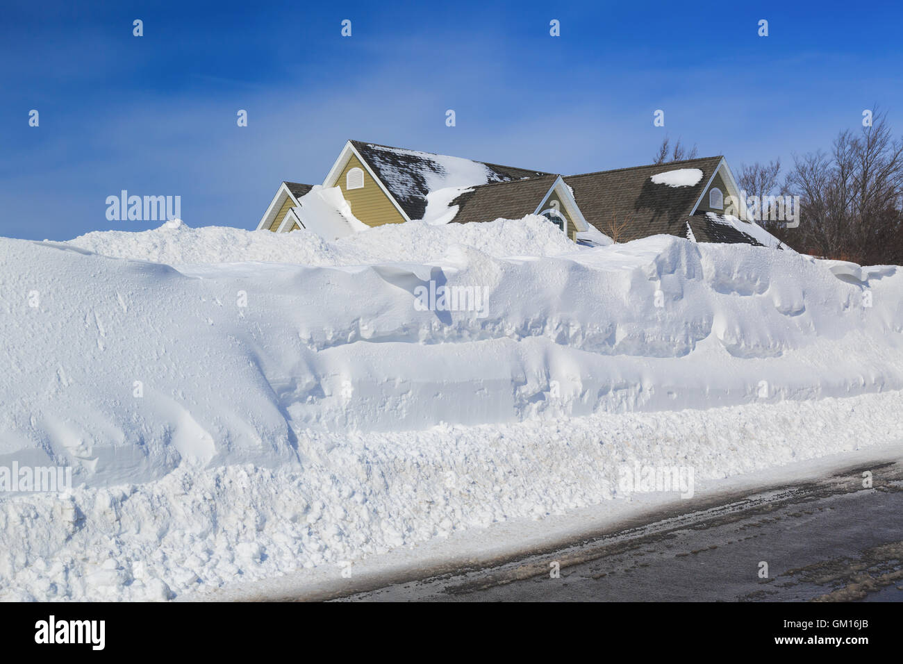 Snowbanks elevata su entrambi i lati di una strada arato in un quartiere urbano. Foto Stock