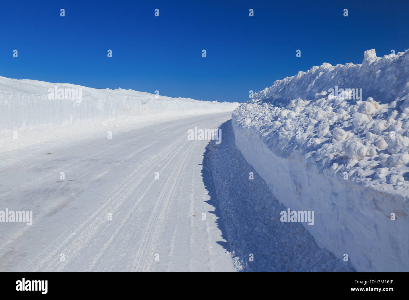 Una strada rurale con alta snowbanks su entrambi i lati. Foto Stock