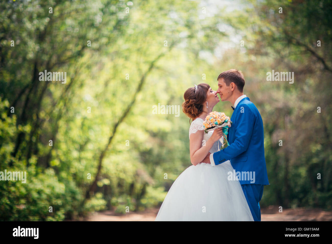 Giovane sposa e lo sposo abbracciando contro lo sfondo della foresta e la strada. Foto Stock