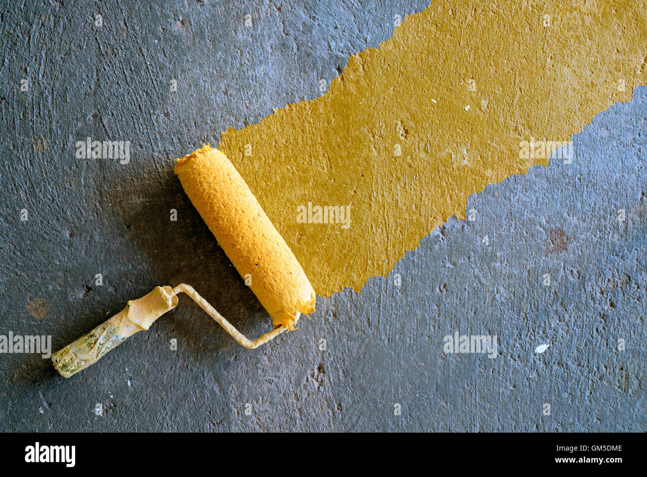 Vernice gialla rullo su sfondo di calcestruzzo Foto Stock