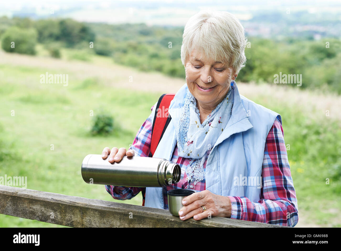 Senior donna con drink dal pallone mentre a piedi Foto Stock
