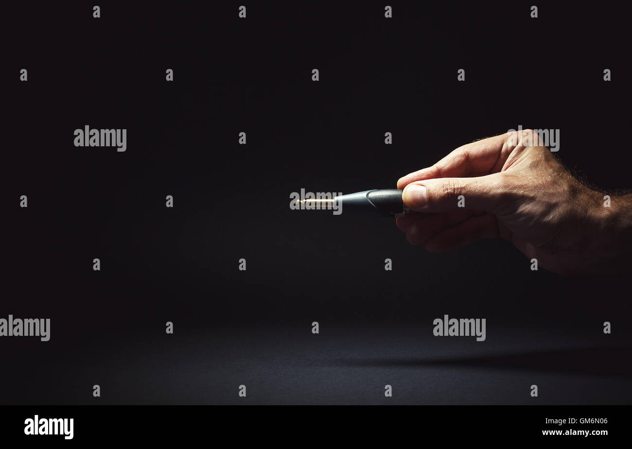 Composizione concettuale, maschio mano che tiene un martinetto, simbolicamente che rappresentano un problema di connessione. Foto Stock