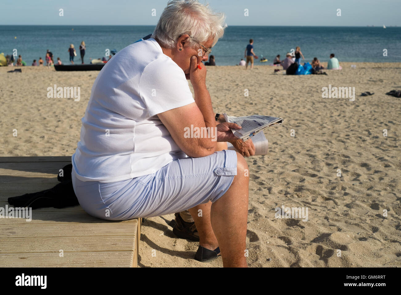 Donna che legge il giornale nel tardo pomeriggio di sole a Gyllyngvase Beach, Falmouth, Cornwall. 24 Agosto 2016 Foto Stock