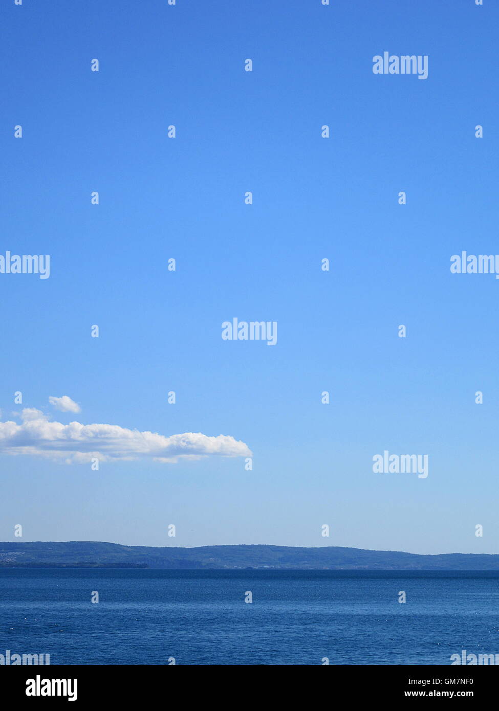 Telaio completo colpo di blu del mare e del cielo con le nuvole e le montagne Foto Stock