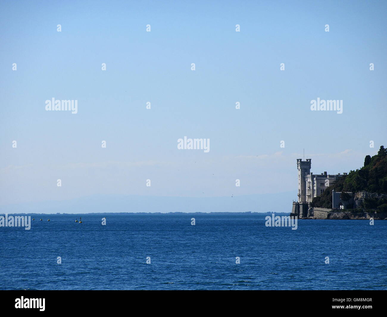Telaio completo colpo di blu del mare e del cielo con castello in pietra e rocce sulla destra Foto Stock