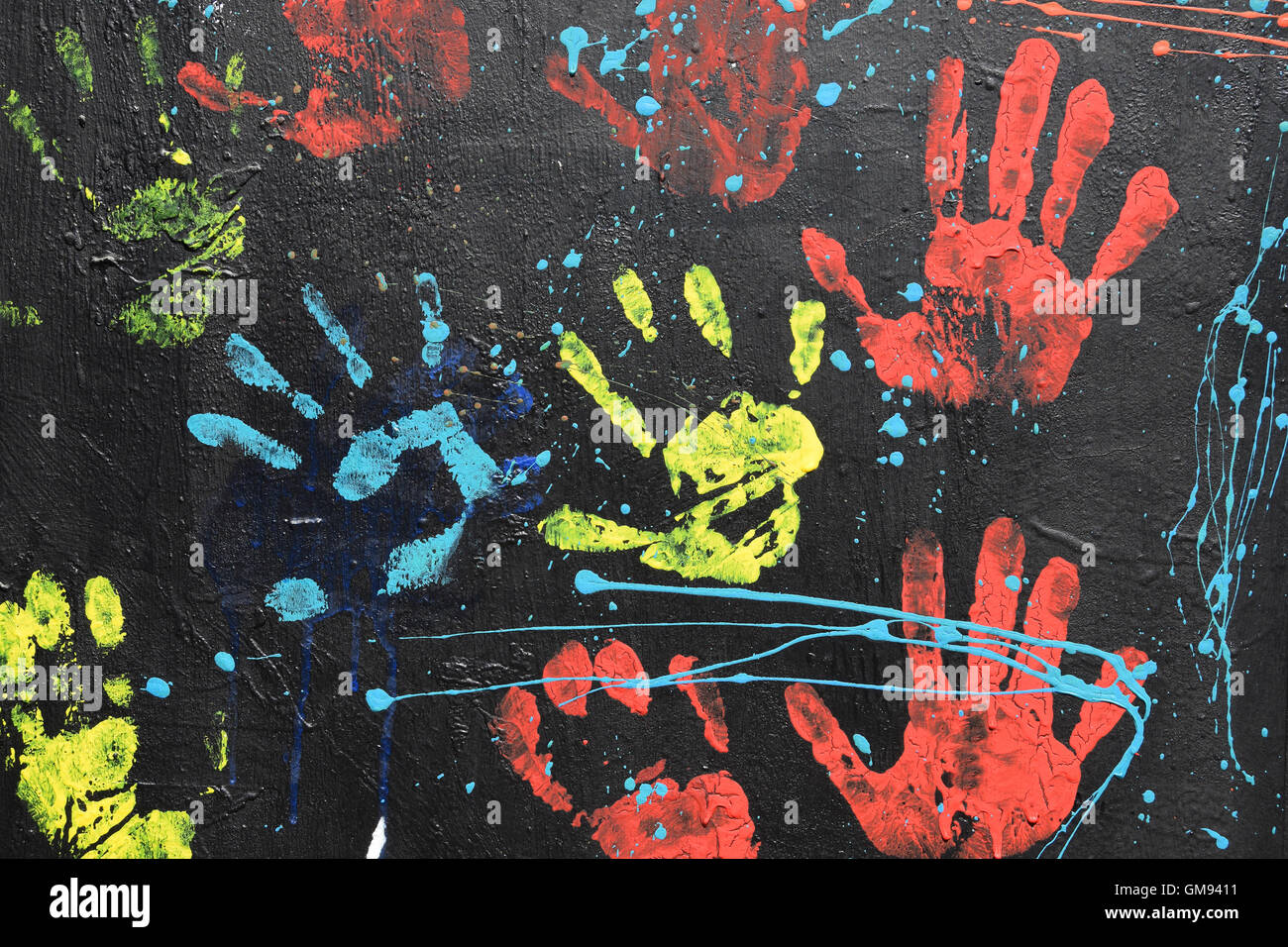 Handprints disordinato e gocce di vernice sulla parete testurizzata sfondo. Colorate impronte mano configurazione astratta. Foto Stock