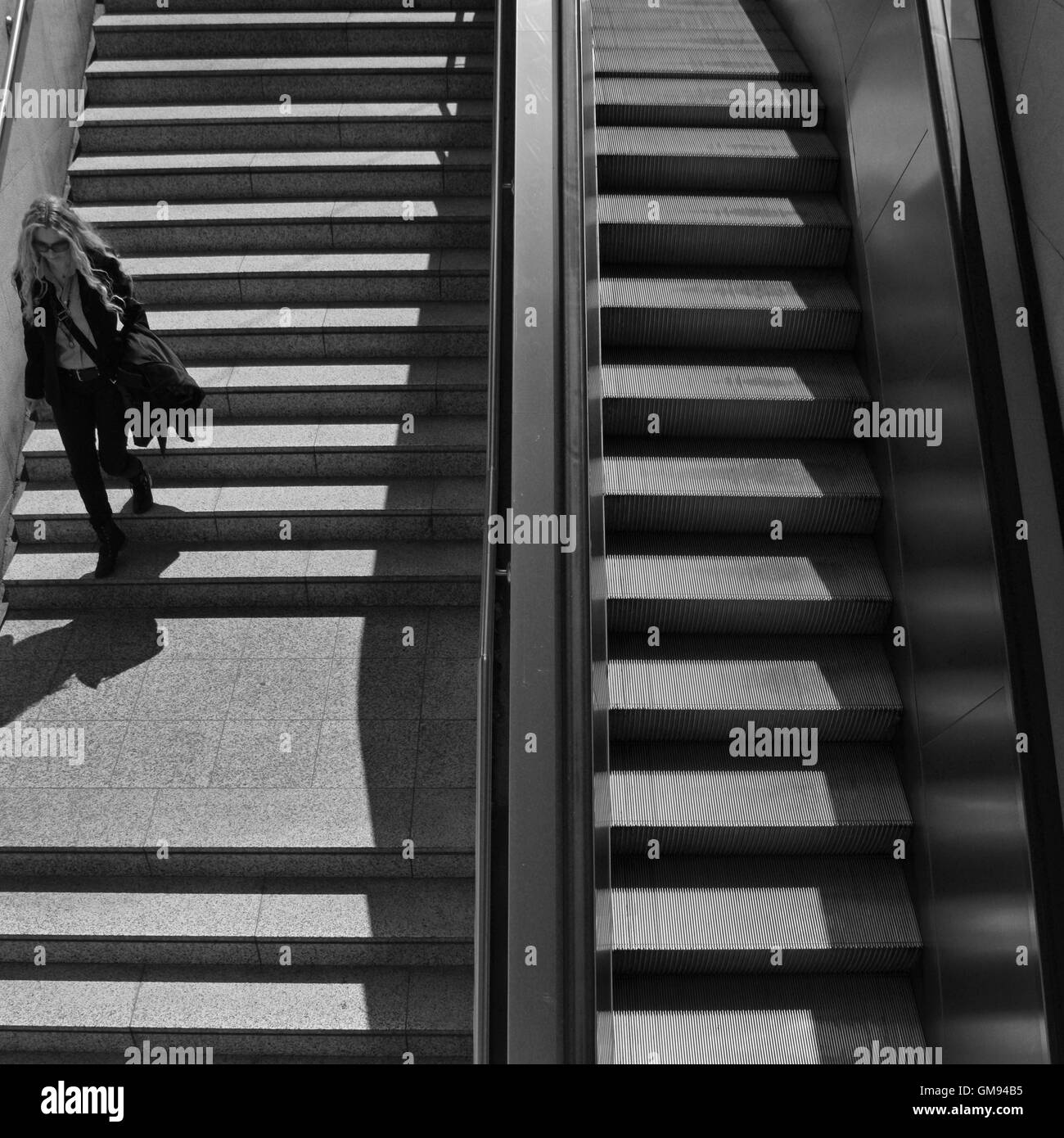 La donna per le scale della metropolitana stazione della metropolitana nel centro di Atene, Grecia. In bianco e nero. Foto Stock
