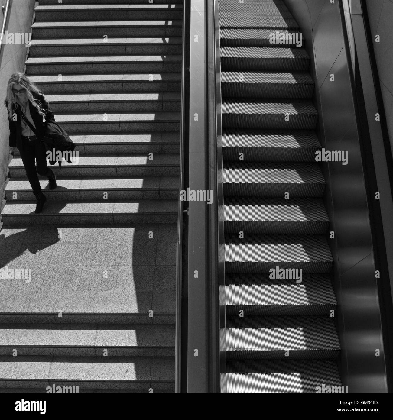 La donna per le scale della metropolitana stazione della metropolitana nel centro di Atene, Grecia. In bianco e nero. Foto Stock