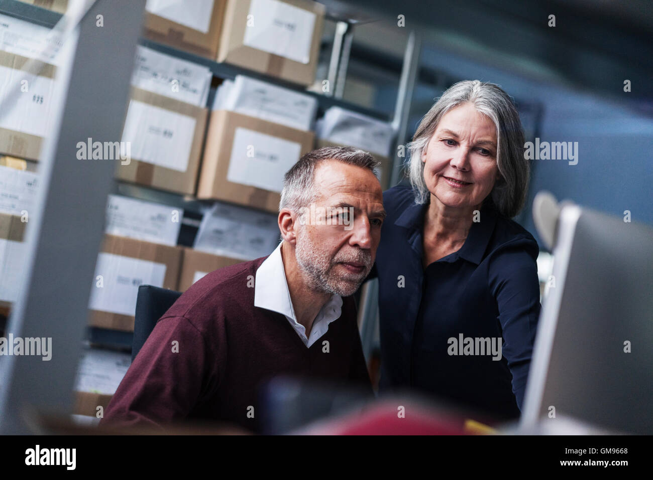 Senior donna e uomo in una fabbrica a scrutare Foto Stock