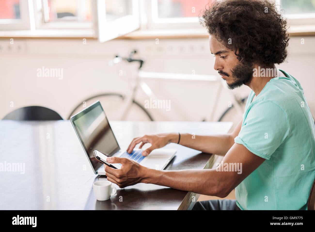 Giovane uomo in ufficio utilizzando laptop Foto Stock