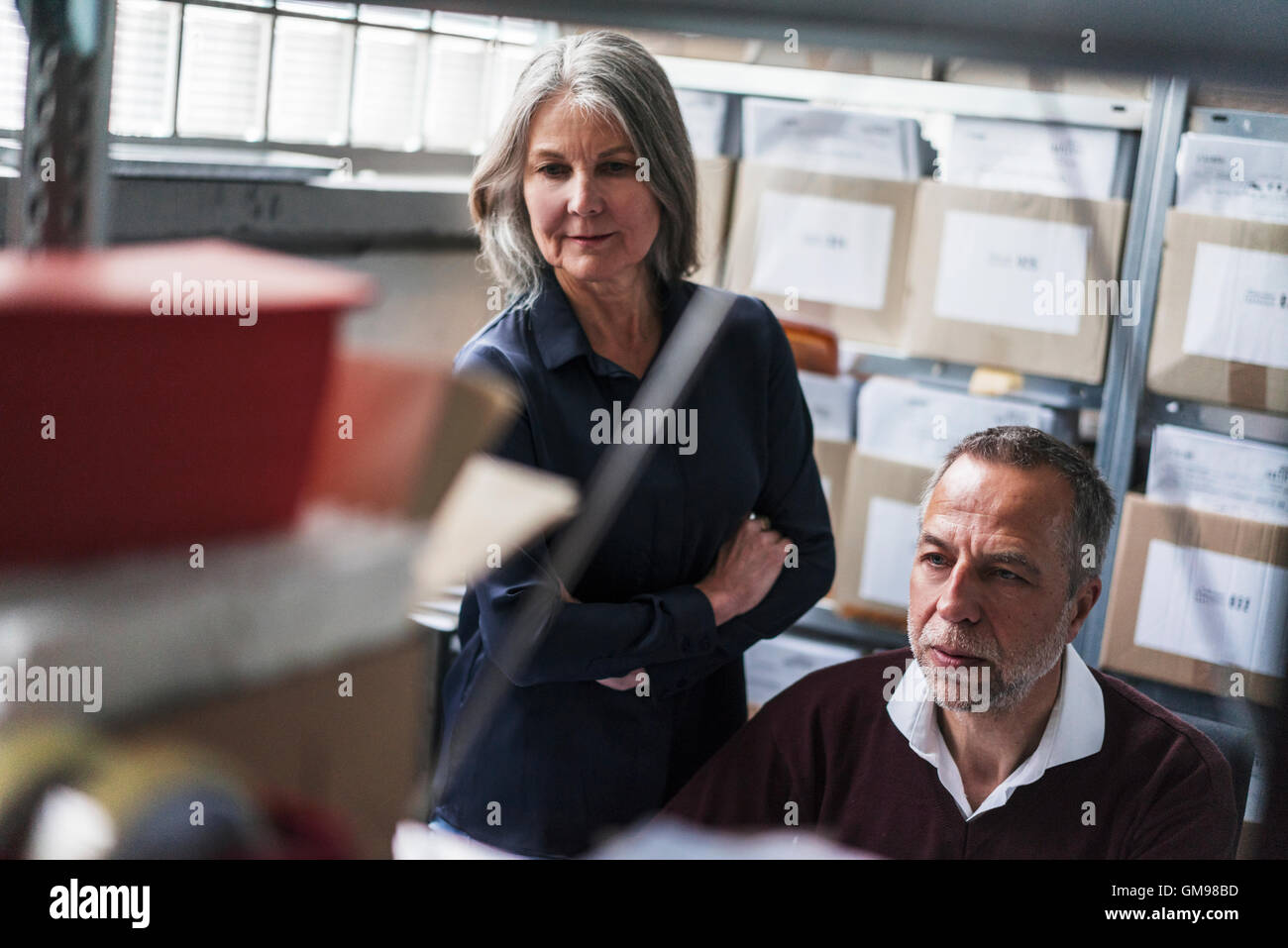 Senior donna e uomo in una fabbrica a scrutare Foto Stock