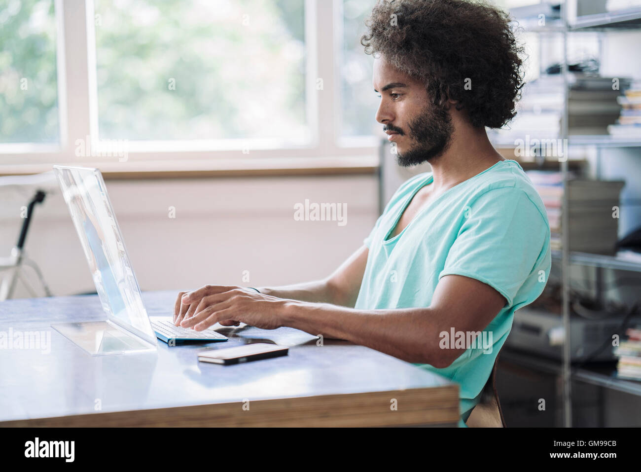 Giovane uomo che lavora in biblioteca, utilizzando computer futuristico Foto Stock
