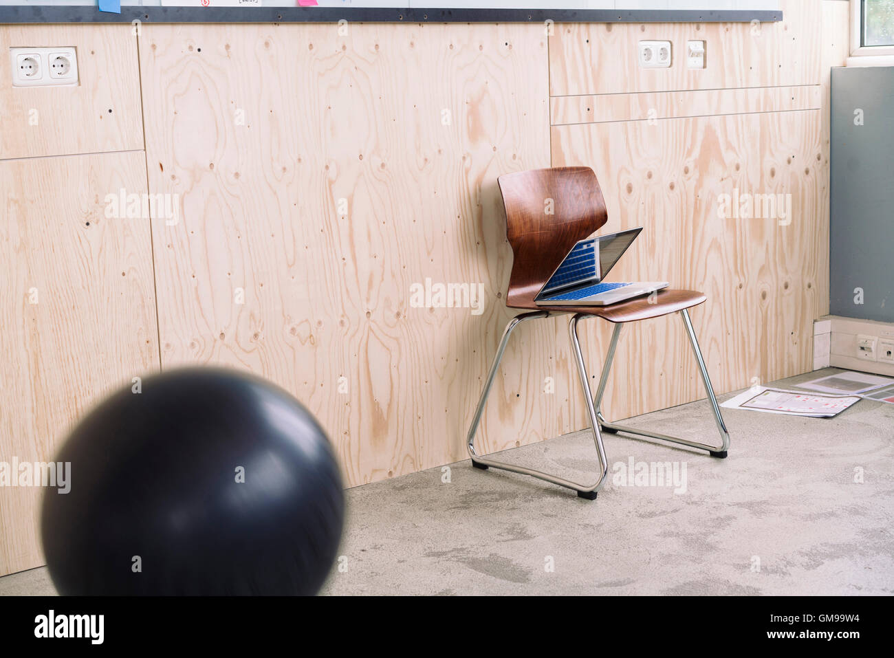 Laptop sulla sedia di legno accanto alla palla Foto Stock