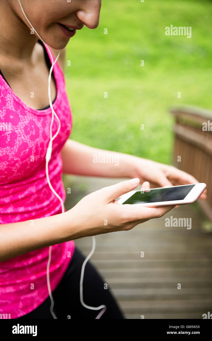 Attività sportive giovane donna con lo smartphone e auricolari Foto Stock