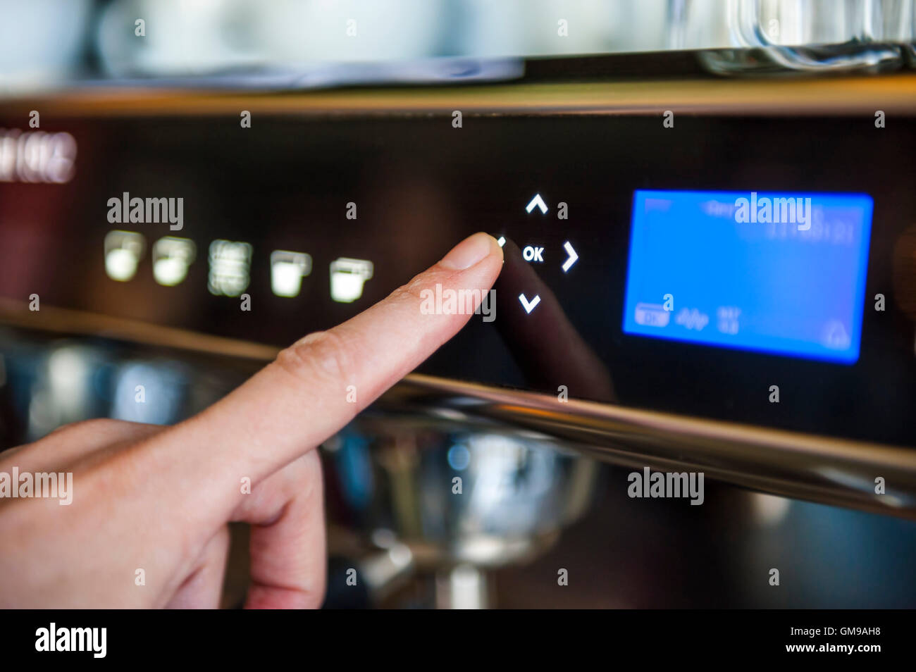 Dito spingendo il pulsante digitale sulla macchina da caffè Foto Stock