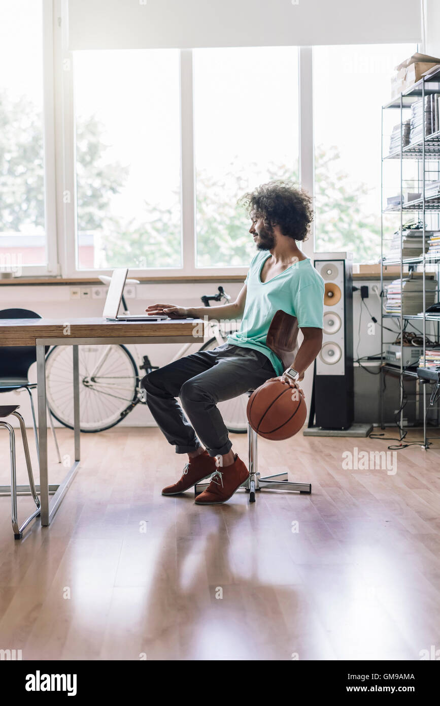 Giovane uomo giocando con il basket in ufficio Foto Stock