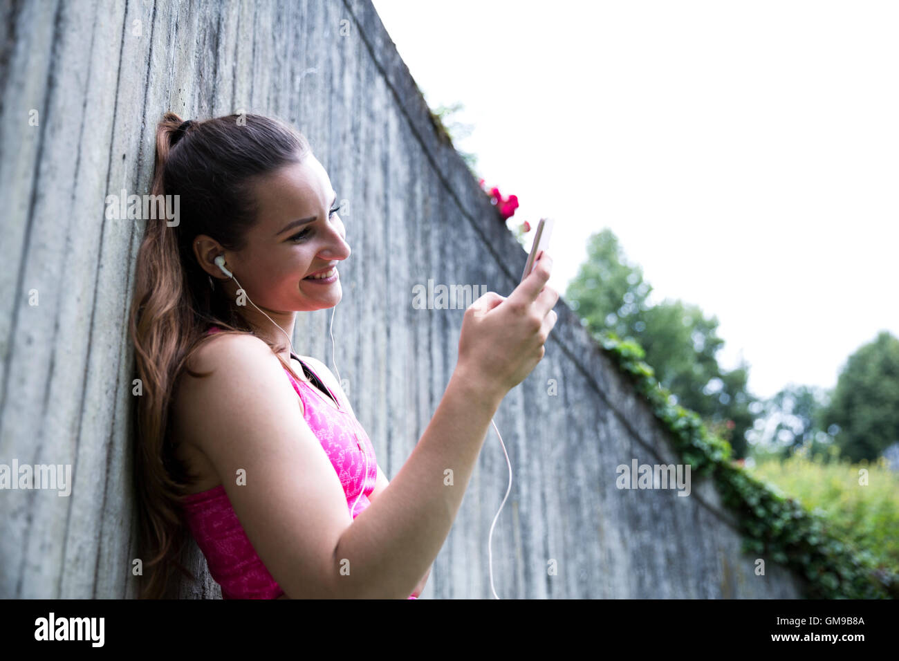 Attività sportive giovane donna con lo smartphone e auricolari Foto Stock