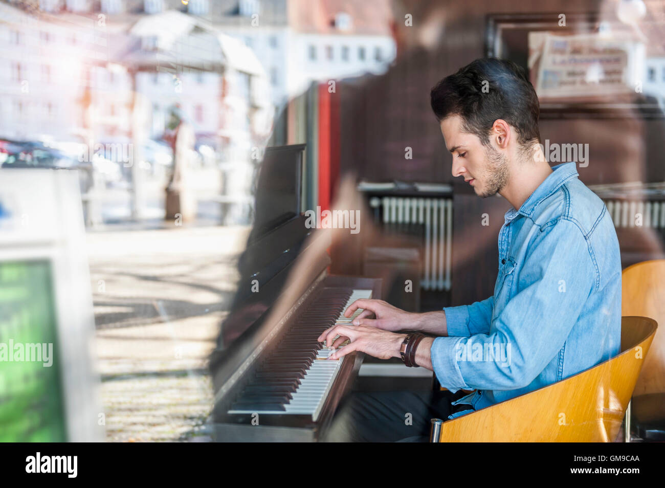 Giovane uomo suonare il pianoforte in un cafe Foto Stock