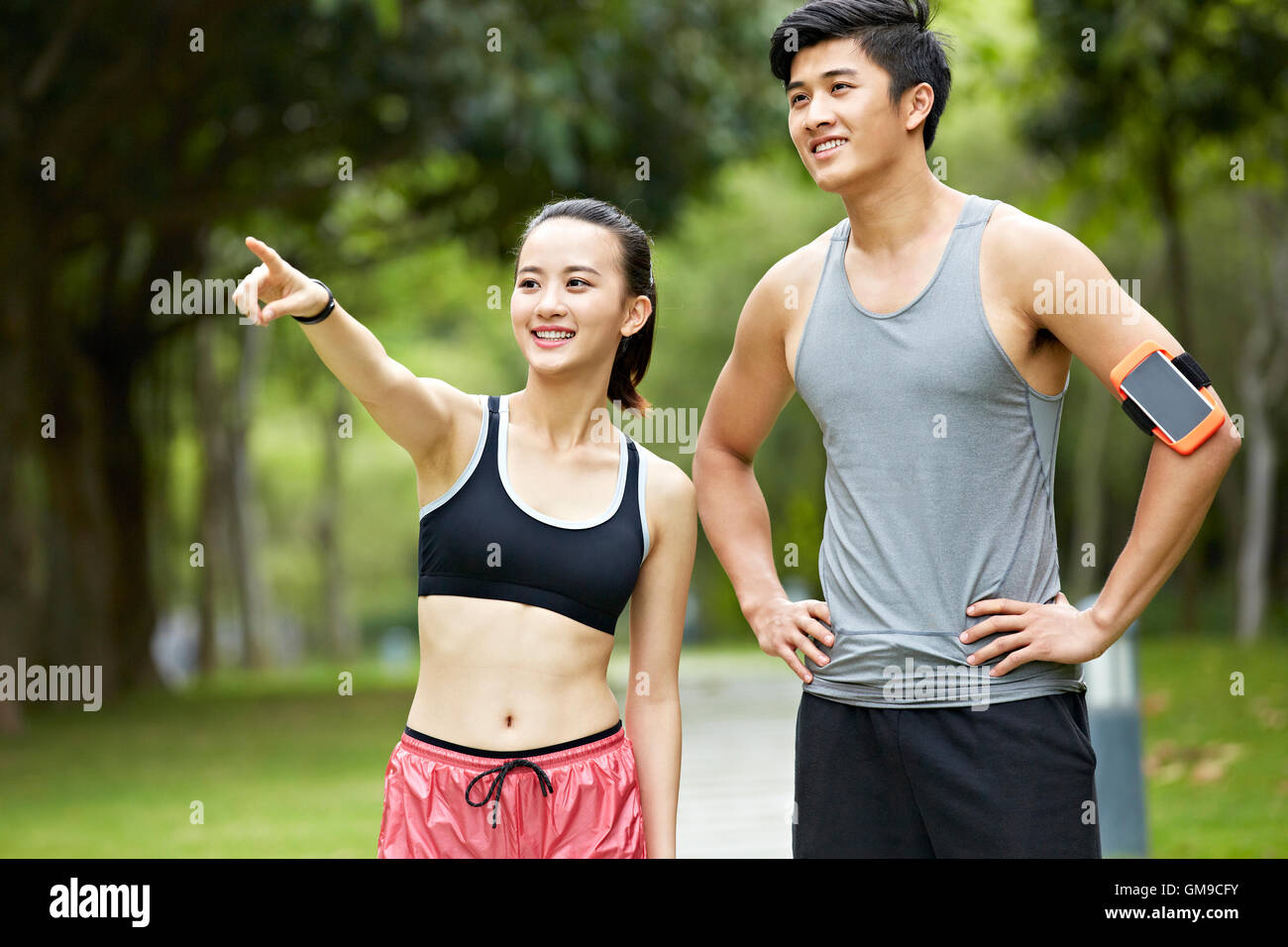 Giovane coppia asiatica che esercitano nel parco, donna rivolti a qualcosa in distanza. Foto Stock