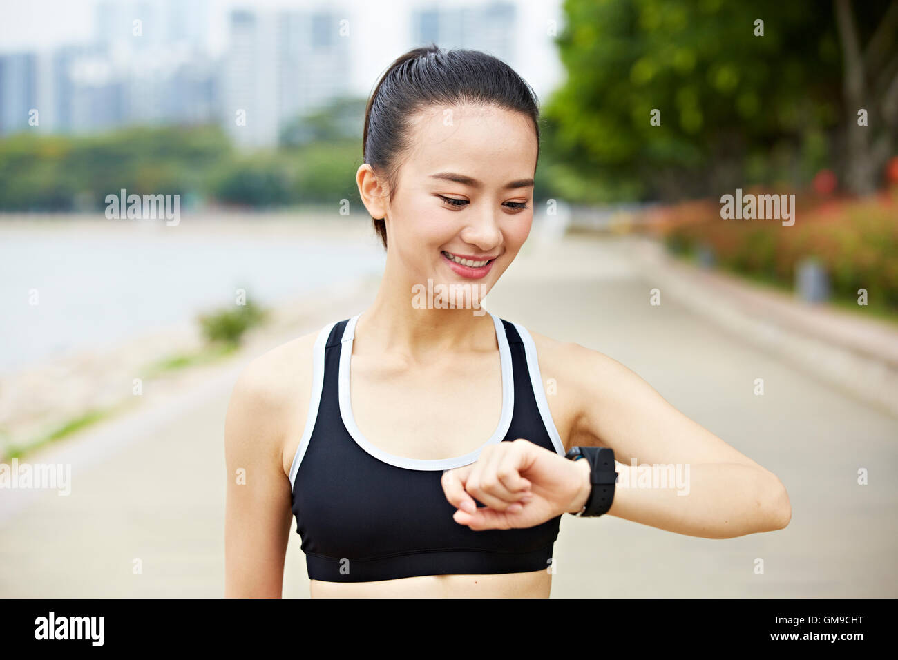 Giovane donna asiatica runner guardando orologio fitness. Foto Stock