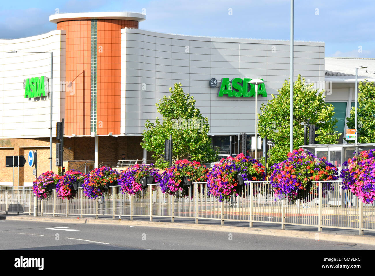 Ventiquattro ore supermercato Asda shopping center nel Rugby Town Center con summer flower visualizza lungo la strada a doppia carreggiata Warwickshire England Regno Unito Foto Stock