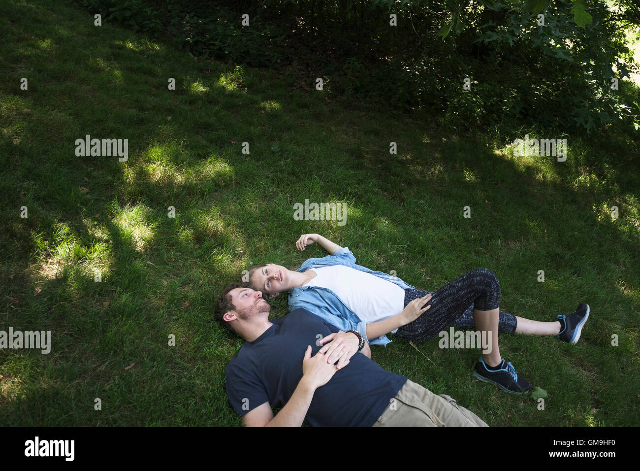 Coppia giacendo su erba in foresta Foto Stock