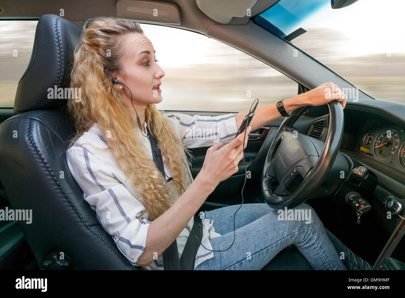 Donna che utilizza il telefono cellulare durante la guida auto Foto Stock