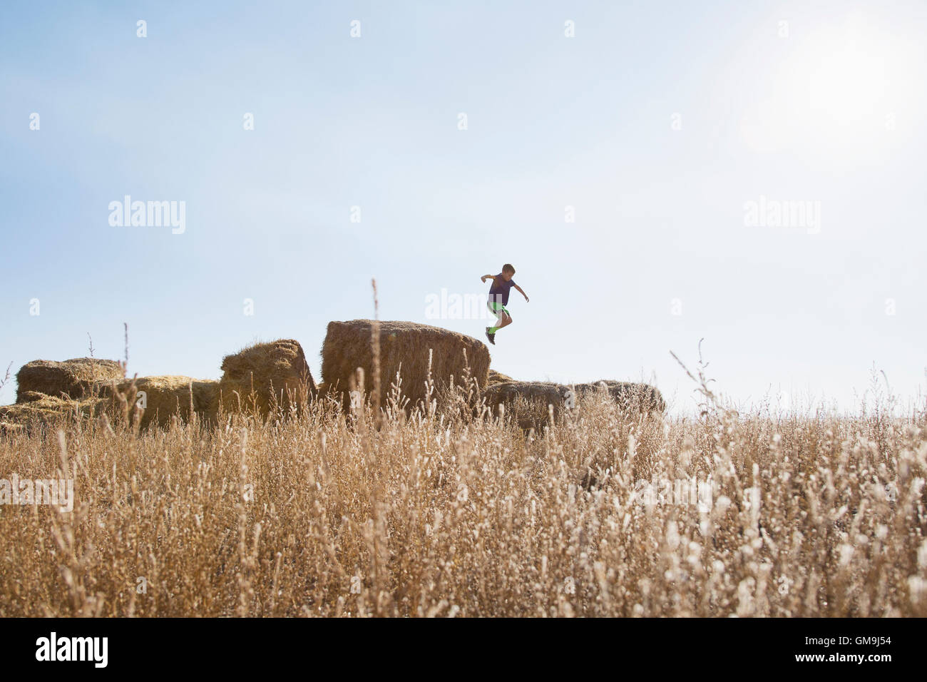 Ragazzo (6-7) il salto sulla balla di fieno Foto Stock