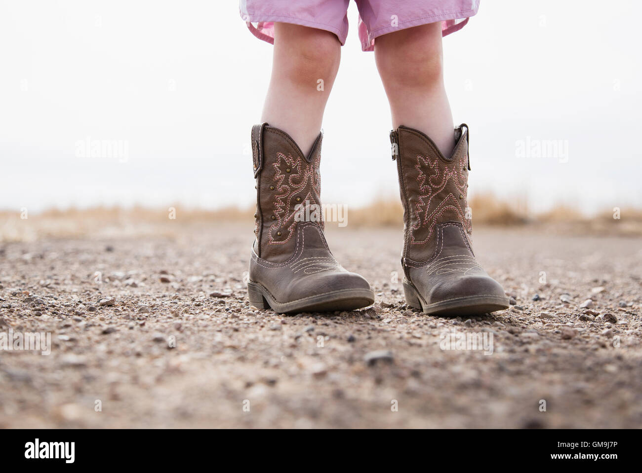 Sezione bassa della bambina (18-23 mesi) indossare stivali da cowboy Foto Stock