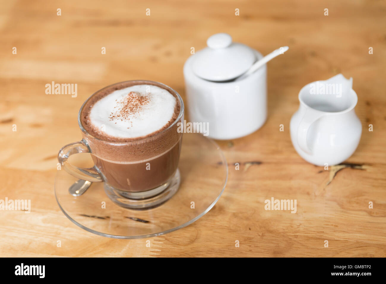 Cioccolata calda bevanda al cioccolato con zucchero e sciroppo mug sulla scrivania in legno Foto Stock