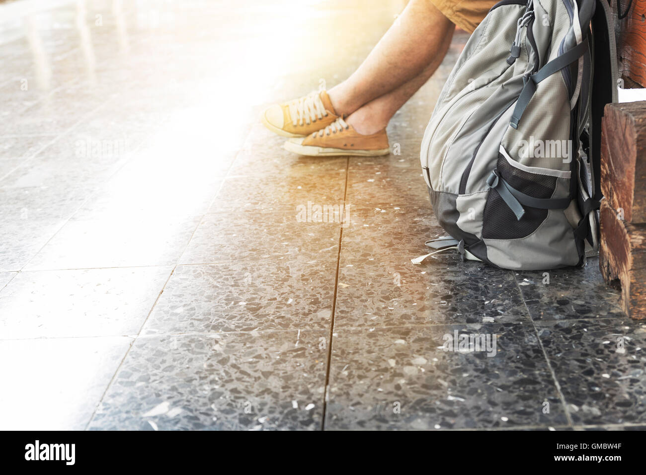 Giovane con zaino e seduta in attesa su piattaforma alla stazione ferroviaria - Concetto di viaggio Foto Stock
