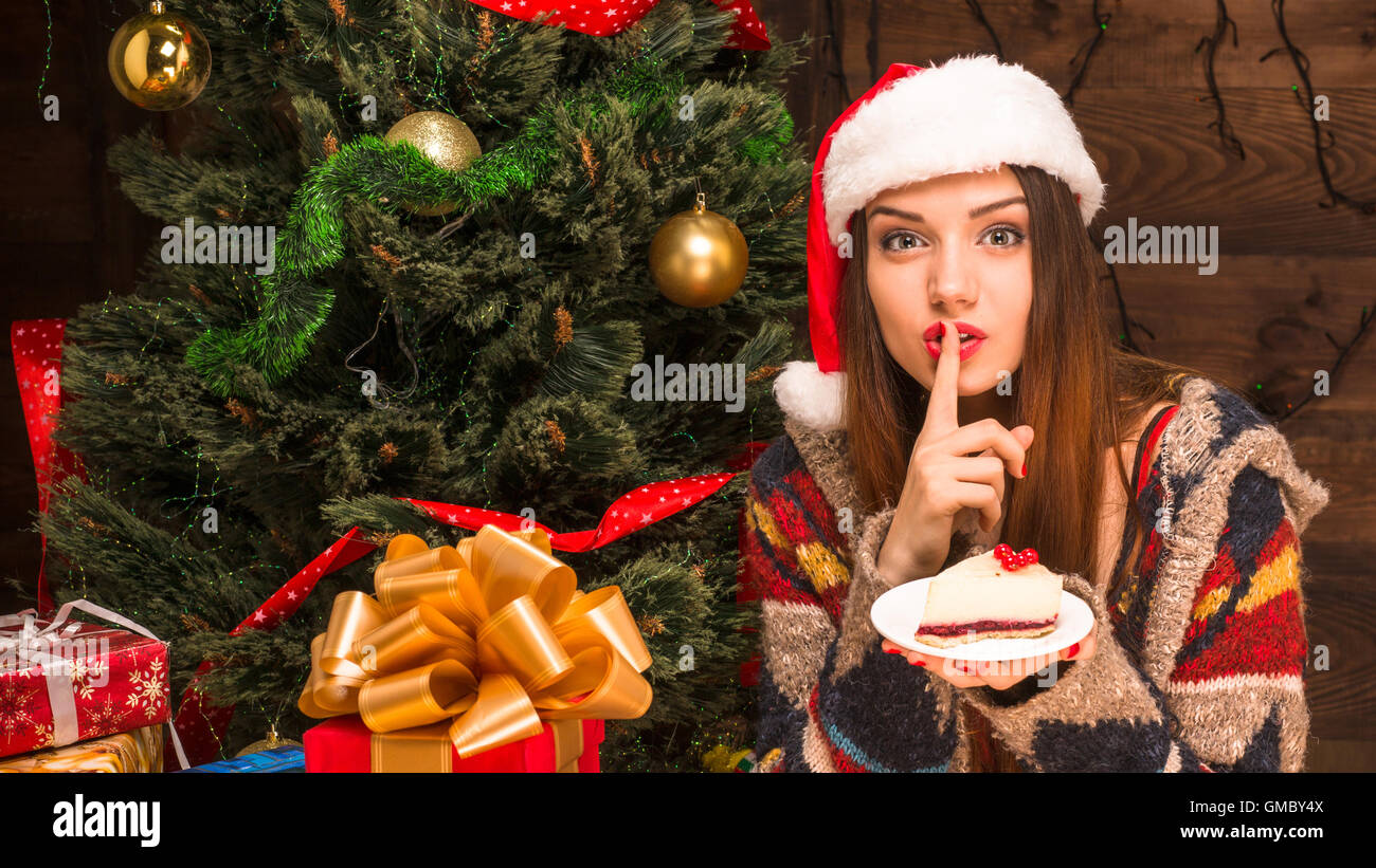 Bella ragazza seduta vicino al Nuovo Anno Albero e mangiare una torta deliziosa Foto Stock