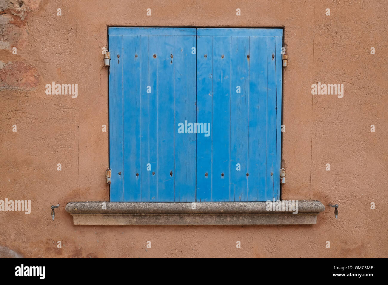 Con persiane blu finestra con ocra parete colorata. Roussillon Vaucluse Provence, Francia. Foto Stock